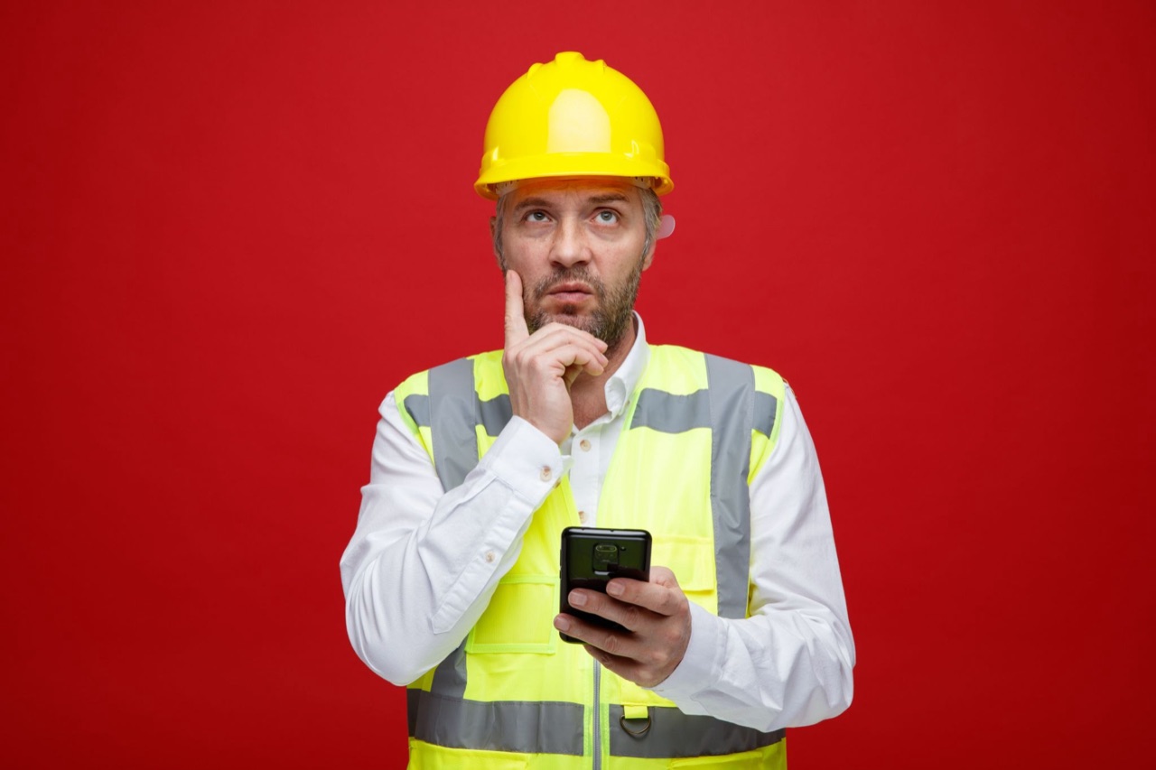 Builder in construction uniform using a smartphone to plan social media content